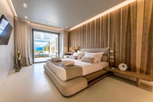 a bedroom with a large bed and a large window at Avgoustos Suites Naxos in Naxos Chora