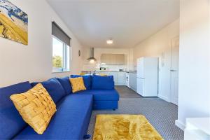 a blue couch in a living room with a kitchen at The Mindrum - Properties Unique in North Shields