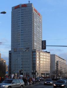 a tall building with cars on a busy city street at Arkadia Centrum - Pokoje in Warsaw