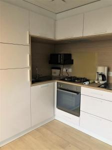 亞貝克的住宿－Vakantiehuis te Jabbeke - Oostende - Brugge，厨房配有白色橱柜和炉灶烤箱。