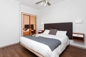 a bedroom with a large white bed and a chair at Apartamentos Villa Florida in Caleta De Fuste +30 photos
