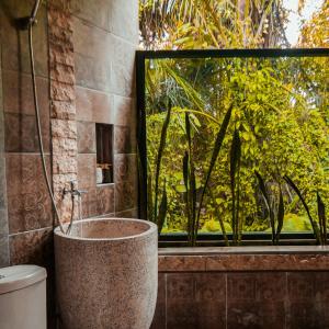 un bagno con vasca accanto a una finestra di Villa Kamar Tamu Selomartani a Sleman