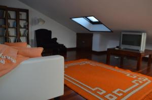 ein Wohnzimmer mit einem Sofa und einem TV in der Unterkunft Fogar de Breogán ÁTICO-DÚPLEX in Caldas de Reis
