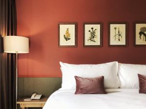a bedroom with a red wall with a bed and a lamp at The Raintree Hotel Chiang Mai in Chiang Mai