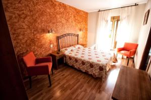 a bedroom with a bed and two red chairs at Alojamiento Covadonga in Cangas de Onís