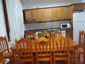 eine Küche mit einem Holztisch mit Stühlen und einem weißen Kühlschrank in der Unterkunft Casa Rural Rio Canto in El Hornillo