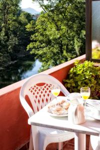 - une table blanche avec deux verres de vin sur un balcon dans l'établissement Alojamiento Covadonga, à Cangas de Onís