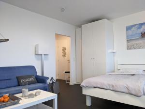 een slaapkamer met een bed en een blauwe bank bij Luv & Lee - Meerblick 34 in Sankt Peter-Ording