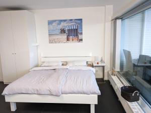 a white bedroom with a bed and a window at Luv & Lee - Meerblick 34 in Sankt Peter-Ording
