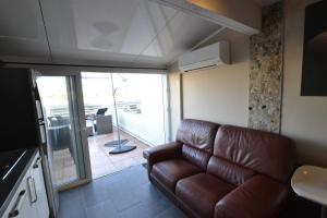 un salon avec un canapé en cuir brun et un balcon dans l'établissement Studio Naturiste CAPTIVE Héliopolis FG 13, au Cap d'Agde
