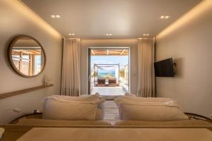 a bedroom with a bed and a mirror and a window at Avgoustos Suites Naxos in Naxos Chora