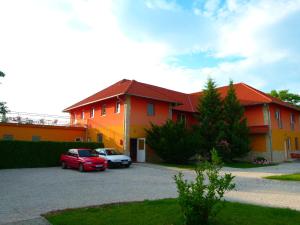 a house with two cars parked in a parking lot at Wellness Park Pension in Gyenesdiás