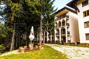 a large building with a umbrella in front of it at Луксозен Апартамент Мечи Чал - Апартхотел Манастира 2 in Pamporovo