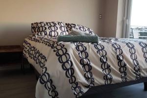 a bed with a black and white blanket and pillows at Espectacular atardecer porteño-Viña in Viña del Mar