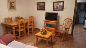 uma sala de estar com uma televisão e uma mesa e cadeiras em Casa Rural los Portalillos I em Navatalgordo
