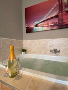 a bottle of champagne and two glasses on a bath tub at Garsoniera Riviera in Bacău