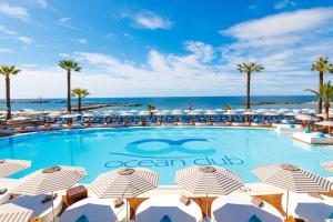 una piscina con sombrillas y el océano en el fondo en First Line Luxury Penthouse, Puerto Banús, Marbella, en Marbella