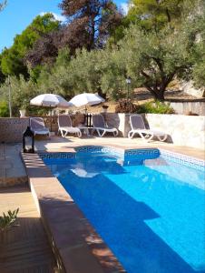 a swimming pool with chairs and umbrellas next to at Casa Rural Las Molina in Frigiliana