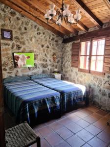 ein Schlafzimmer mit einem Bett in einer Steinmauer in der Unterkunft Casa Rural Menta y Canela in Tórtoles