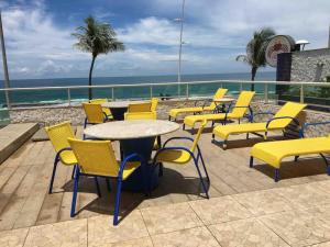 a group of yellow chairs and tables on a patio at Apartamento Incrível in Salvador