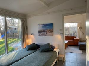 a bedroom with a bed and a large window at Vakantiehuis Zonlicht in Zoutelande