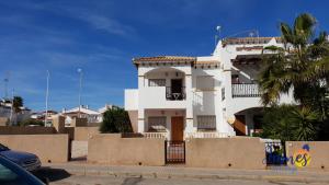 une maison blanche avec un palmier en face dans l'établissement La Ciñuelica R14 First Floor Apartment L126, à Orihuela