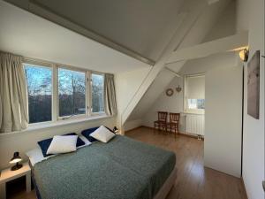 a bedroom with a bed and two windows at Vakantiehuis Zonlicht in Zoutelande