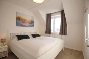 a white bed in a bedroom with a window at Haffblick Wohnung 48 in Boltenhagen