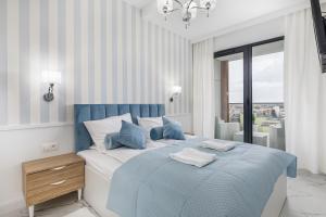 a bedroom with a blue and white bed and a window at Prestiżowe Apartamenty Natural Darłówko by Renters in Darłowo