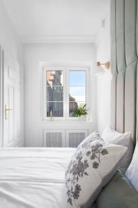 a white bedroom with a bed and a window at Elite Apartments Old Town Deluxe in Gdańsk