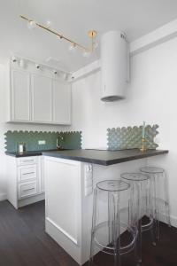 a kitchen with white cabinets and bar stools at Elite Apartments Old Town Deluxe in Gdańsk