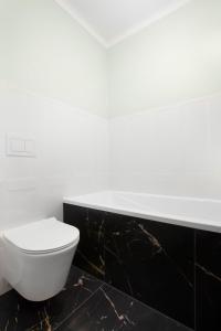 a bathroom with a white toilet and black tiles at Elite Apartments Old Town Deluxe in Gdańsk