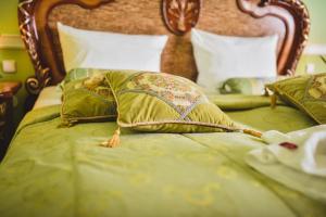 ein Bett mit einer grünen Bettdecke und Kissen darauf in der Unterkunft Zámek Kamenný Dvůr in Kynšperk nad Ohří