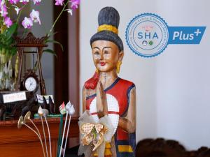 una estatua de madera de una mujer sosteniendo una flor en The Orchid House - SHA Extra Plus en Kata Beach