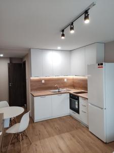 uma cozinha com armários brancos, uma mesa e um frigorífico em Studio 16A Vasil Aprilov 64 - Plovdiv em Plovdiv