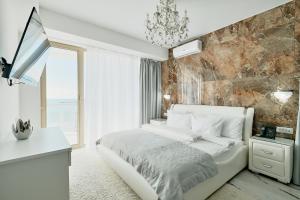a bedroom with a white bed and a stone wall at "Serenity Premium apartments" с панорамным видом на море in Sochi