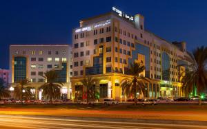 un bâtiment avec des voitures garées en face d'une rue dans l'établissement City Seasons Hotel & Suites Muscat, à Mascate