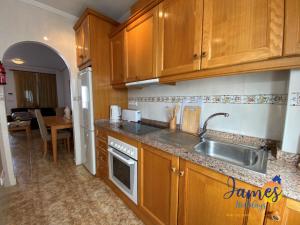 una cocina con armarios de madera y fregadero en La Ciñuelica R14 1st Floor Apartment Com Pool L182, en Orihuela