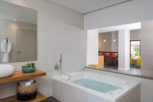 a bath tub sitting next to a sink in a bathroom at Oasis Spa Club Dead Sea Hotel in Ein Bokek