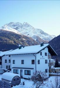 un bâtiment recouvert de neige avec des montagnes en arrière-plan dans l'établissement Das Astrid, à Pettneu am Arlberg