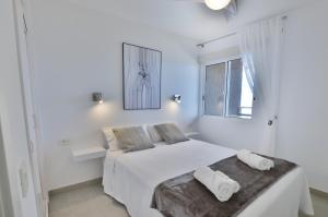 a white bedroom with a bed and a window at Costa Isora in Puerto de Santiago +37 photos