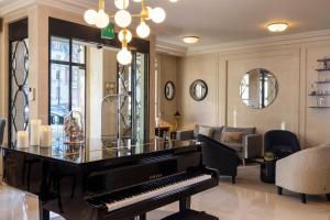 une chambre avec un piano et un salon avec un canapé dans l'établissement Hôtel de Banville, à Paris