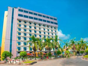 un grand bâtiment avec des palmiers devant lui dans l'établissement FAYA Hotel, à Douala