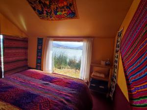 a bedroom with a bed and a large window at Quechua lodge Titicaca in Puno