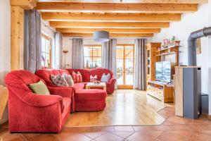 ein Wohnzimmer mit einem roten Sofa und einem TV in der Unterkunft Sonnenchalet 1 im Salzburger Lungau in Mariapfarr