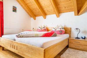 Schlafzimmer mit einem Holzbett mit roten und weißen Kissen in der Unterkunft Sonnenchalet 1 im Salzburger Lungau in Mariapfarr