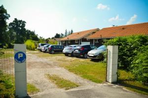 a parking lot with cars parked in front of a house at Hotel Les Pins in Hourtin