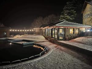 a house with a pool in the snow at night at Хотелски комплекс САНЯ in Apriltsi