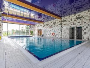 a large swimming pool with blue water in a building at VacationClub – 5 Mórz Sianożęty Apartament 1J/2 in Sianozety