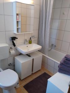 a bathroom with a sink and a toilet and a tub at Apartment 365 mit Sauna, Schwimmbad und Fitness in Schönwald
